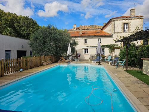 a large blue swimming pool in front of a house at La maison de Léon in Celles-sur-Belle