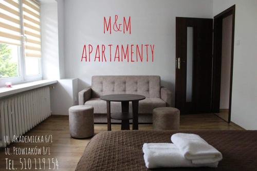 een slaapkamer met een bed, een stoel en een tafel bij M&M apartamenty 2 in Zamość