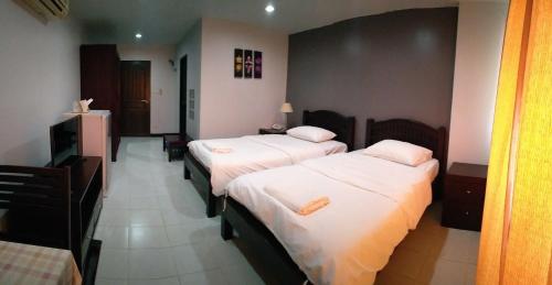 um quarto de hotel com duas camas com lençóis brancos em โรงแรม ศิราภา เรสซิเด้นท์ จำกัด em Chachoengsao