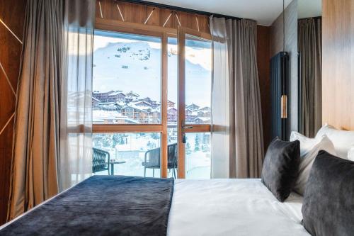 Cette chambre comprend un lit et une grande fenêtre. dans l'établissement Hôtel Le Diamond Rock, à Tignes