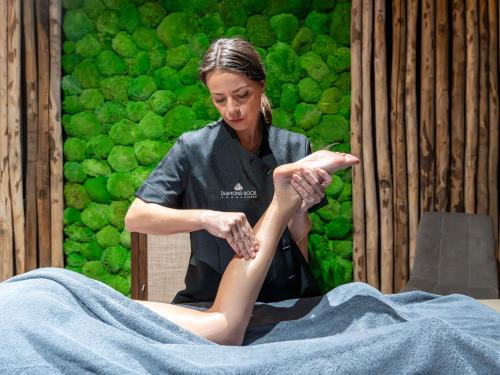 a woman performing a leg massage on a persons leg at Hôtel Le Diamond Rock in Tignes