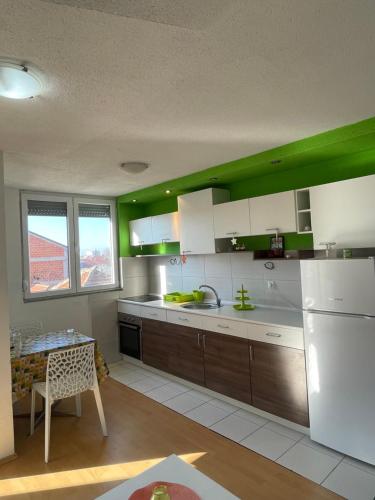 eine Küche mit weißen und grünen Schränken und einem Tisch in der Unterkunft Spirit Apartment 2 in Ohrid