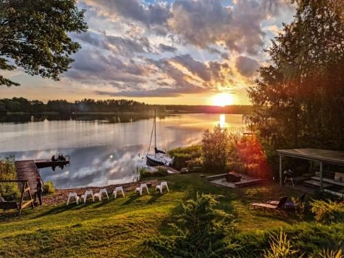 una puesta de sol sobre un lago con un barco en el agua en Sirvis Apartamenty, en Płaska