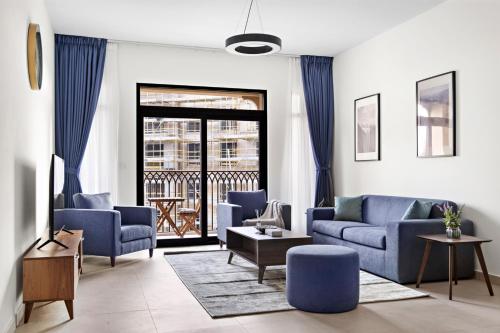a living room with blue couches and a balcony at StoneTree - Luxury 1BR - Best Location for Tourist in Dubai