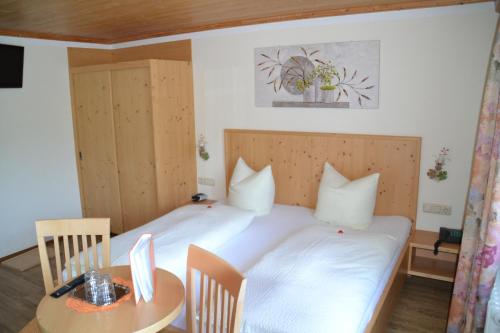 a bedroom with a white bed and a table at Haus Binder in Ried im Zillertal
