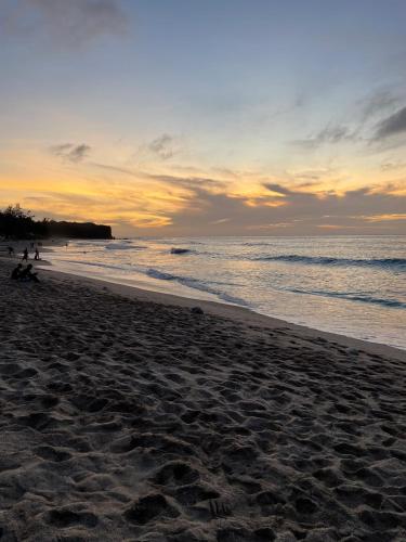 a beach with people on the sand and the ocean at Le Khâlin in Saint-Paul