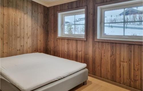 sypialnia z drewnianymi panelami i łóżkiem z dwoma oknami w obiekcie Amazing Home In seral With House A Mountain View w mieście Åseral