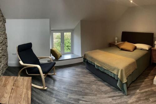 a bedroom with a bed and a chair and a window at Stunningly stylish cottage. in Bradwell