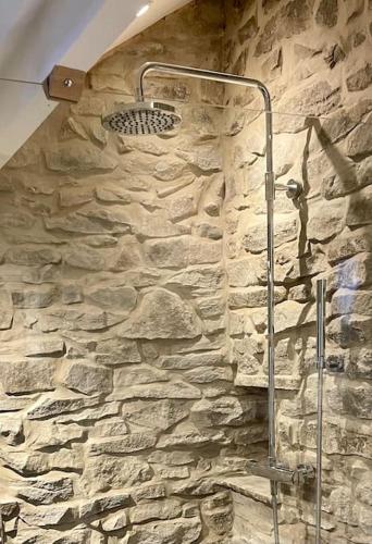 a stone bathroom with a shower in a stone wall at Stunningly stylish cottage. in Bradwell