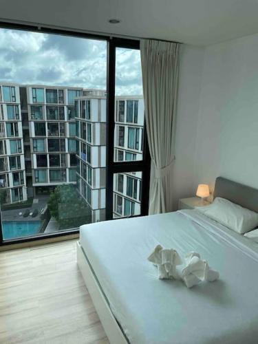 a bedroom with a white bed and a large window at Luxury condo in phuket shopping center in Phuket