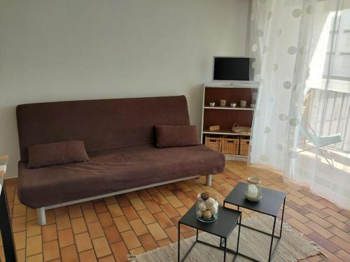 a living room with a couch and two tables at 2min mer Studio Parking Balcon Wifi Clim in Six-Fours-les-Plages