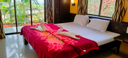 due cigni stesi su un letto con una coperta rossa di Maple Villa a Mahabaleshwar
