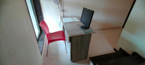 una scrivania con monitor per computer e sedia rossa di Maple Villa a Mahabaleshwar