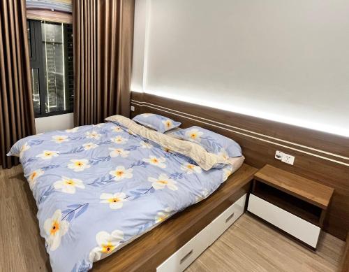 uma cama com um edredão azul com flores em Sky home em Gia Lâm Pho
