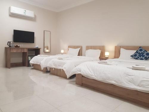 una camera da letto con due letti e una televisione di مورايا Murraya a Abyār ‘Alī