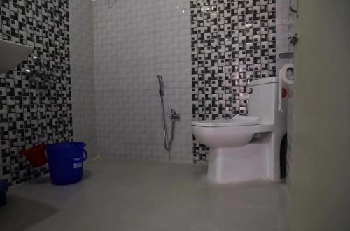 e bagno con servizi igienici su una parete di piastrelle bianche e nere. di Hotel Vivid Tawang a Tawang