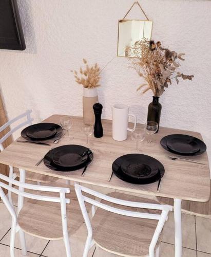 a wooden table with black plates and wine glasses at Le Studio 360 Proche Futuroscope & Arena 1/4 Pers in Chasseneuil-du-Poitou