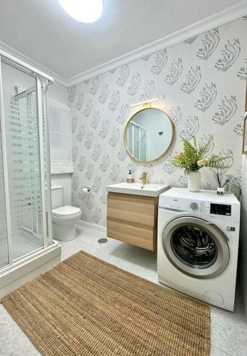 a bathroom with a washing machine and a mirror at Nuevo Torrox Deluxe Beach & Piscina in Torrox