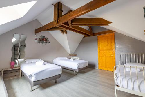 een slaapkamer op zolder met 2 bedden en een houten plafond bij La Belle Grace in Saint-Aignan