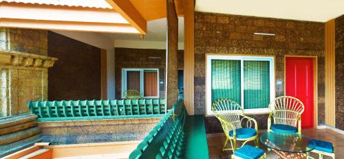 a patio with chairs and a table and a red door at Krishna Beach Resort in Kannur