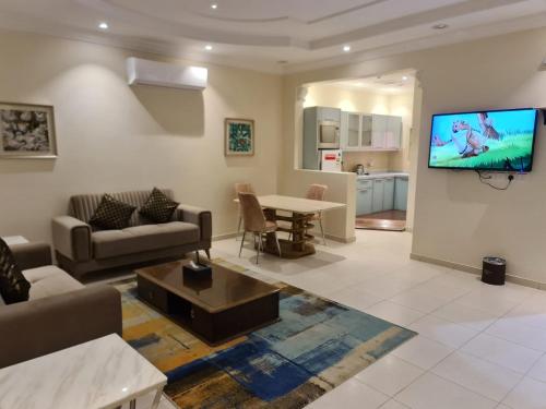 a living room with a couch and a tv on a wall at Dshale Apartments in Taif