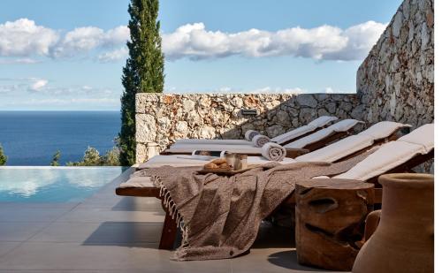 a row of lounge chairs next to a swimming pool at Thelxi's Suite I - Brand New Seaview Suite! in Agios Nikolaos