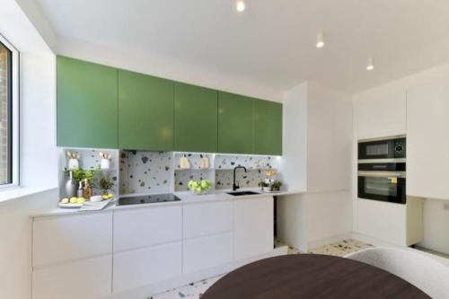 eine Küche mit weißen und grünen Schränken und einem Tisch in der Unterkunft Big 4 Bed House, Close to Gatwick (15 mins) in Redhill