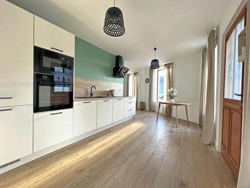 une cuisine avec des armoires blanches et un plancher en bois dans l'établissement Appartement coup de coeur. St Etienne-Rochetaillée, à Saint-Étienne