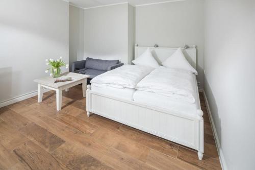 a bedroom with a white bed and a table at Haus Delft Minerva in Juist