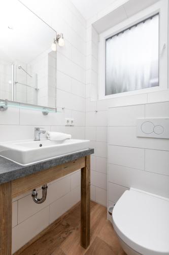 a white bathroom with a sink and a toilet at Haus Delft Jakea in Juist