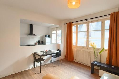 a living room with a table and chairs and a window at Foucault - Appartements - au cœur de Lourdes in Lourdes