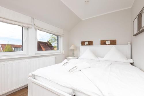 a white bedroom with a white bed and a window at Haus Delft Baoule in Juist