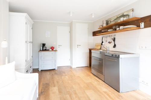 eine Küche mit weißen Schränken und einem Kühlschrank aus Edelstahl in der Unterkunft Haus Delft Argyra in Juist