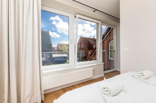 a bedroom with two beds and a large window at Haus Delft Elisa in Juist