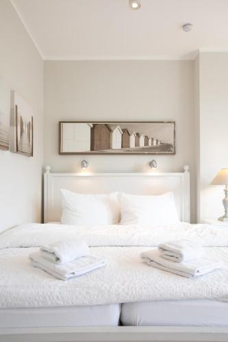 a white bedroom with a white bed with towels on it at Haus Delft Lita in Juist