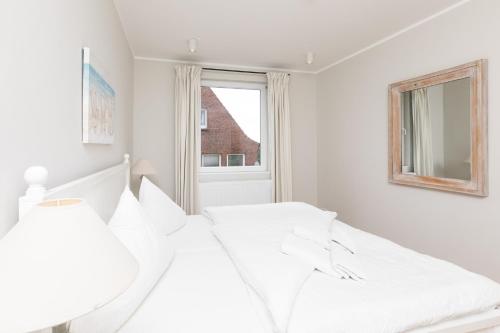 a white bedroom with a bed and a window at Haus Delft Anjola in Juist