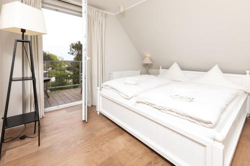 a white bedroom with a bed and a balcony at Haus Delft Jaap Jacoba in Juist