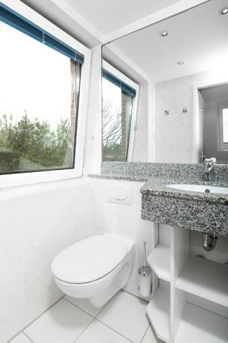 a white bathroom with a toilet and a sink at Haus Delft Ilmenau in Juist