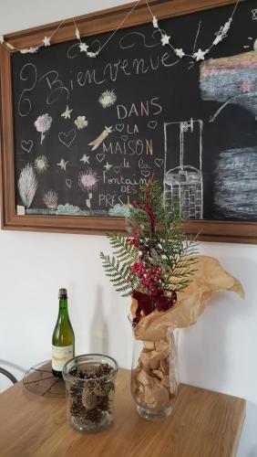 un tavolo con una bottiglia di vino e un vaso con una pianta di Gîte La Fontaine des Prés a Cherbourg en Cotentin
