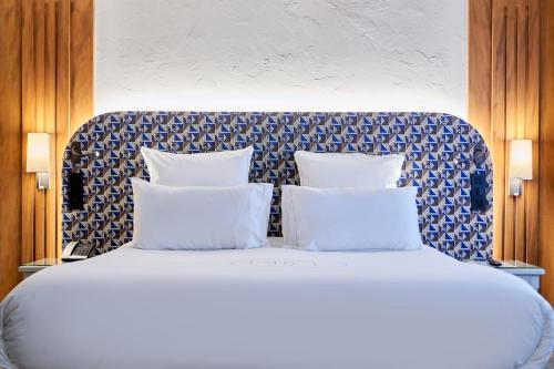 a white bed with two pillows on top of it at Relais & Châteaux La Maison Des Têtes in Colmar
