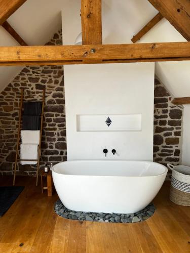 a bath tub in a bathroom with a brick wall at La Maison Gavraise in Gavray