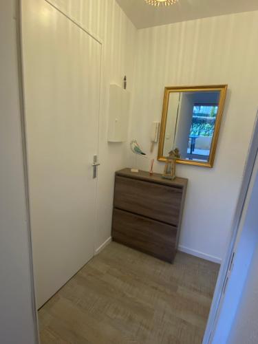 een badkamer met een spiegel en een houten dressoir bij Le Petit Nid du Port Crouesty - Studio au calme in Arzon