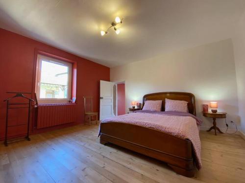 a bedroom with a bed with red walls and a window at Au Lavoir in Vinzelles