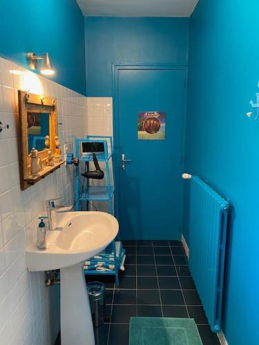 a blue bathroom with a sink and a blue door at Au Lavoir in Vinzelles