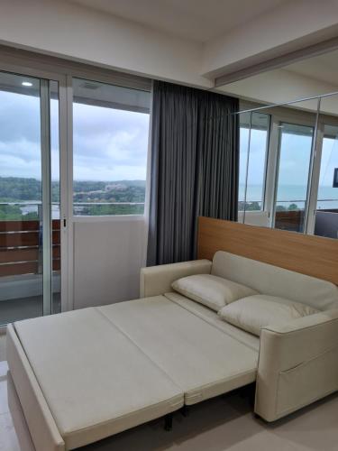 a bedroom with a white bed and glass windows at Nuvasa Bay The Nove Kalani Tower in Telukmataikan