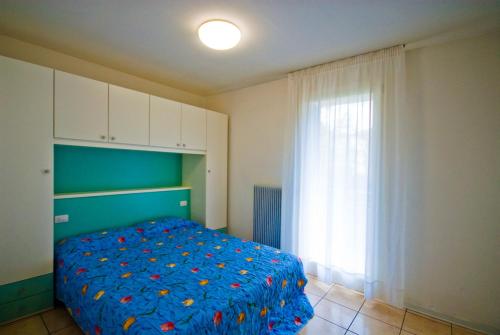 a bedroom with a blue bed and a window at Residence Solemar - Agenzia Cocal in Caorle