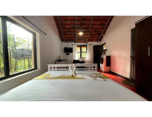 Cama grande en habitación con ventana grande en The Earthen Nest Resort, Canacona, Goa en Poinguinim