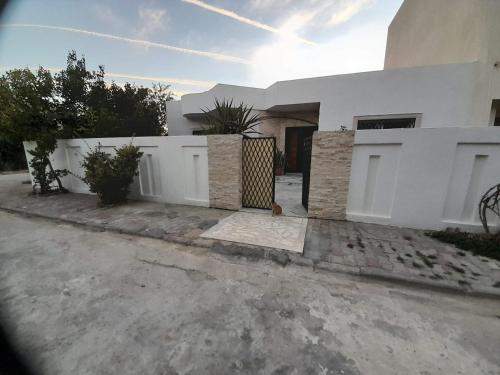 una casa blanca con valla y entrada en Villa des plaisirs, en Borj el Khessous