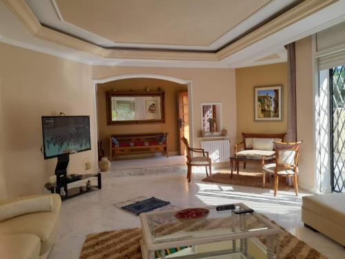 uma sala de estar com um sofá e uma televisão em Villa des plaisirs em Borj el Khessous