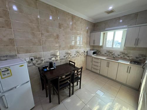 eine Küche mit einem Tisch und einem weißen Kühlschrank in der Unterkunft PRIMOTEL Suites As Salamah in Dschidda